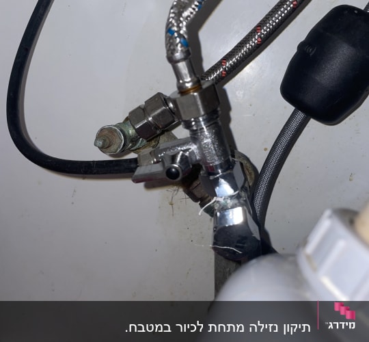 צנרת מתכת עם ברזים וחיבורים מתחת לכיור